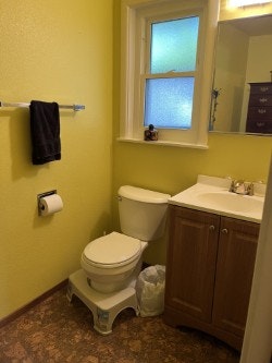 A bathroom with yellow walls, a toilet, sink with cabinet, mirror, window, towel, and toilet paper.