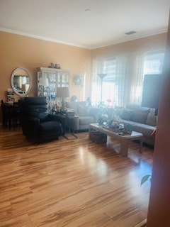 A cozy living room with wooden floors, a couch, chairs, coffee table, and decorative items. Bright with natural light.