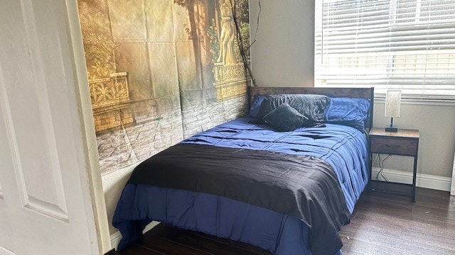 A cozy bedroom setup with a bed featuring blue bedding, a decorative wall tapestry, and a nightstand with a lamp.