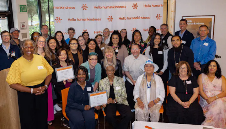 A large group photo of diverse individuals, some holding certificates, at an event by "Hello humankindness."