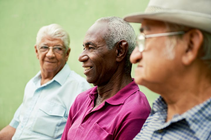 Three elderly men sitting together, smiling and enjoying each other's company.