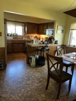 A kitchen and dining area with wooden cabinets, table, chairs, and various items on the countertops.