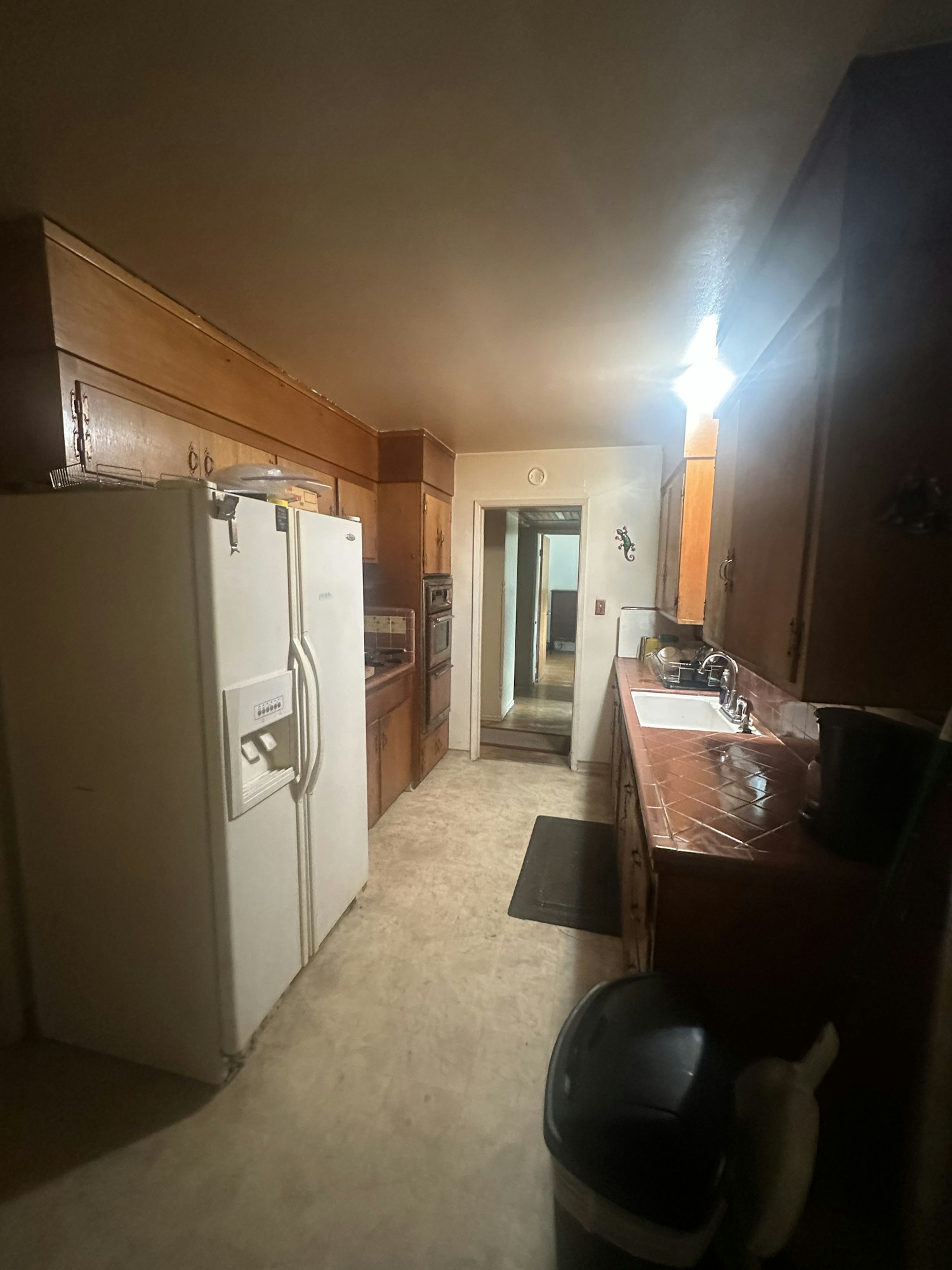 A kitchen with wooden cabinets, a white refrigerator, and a sink.