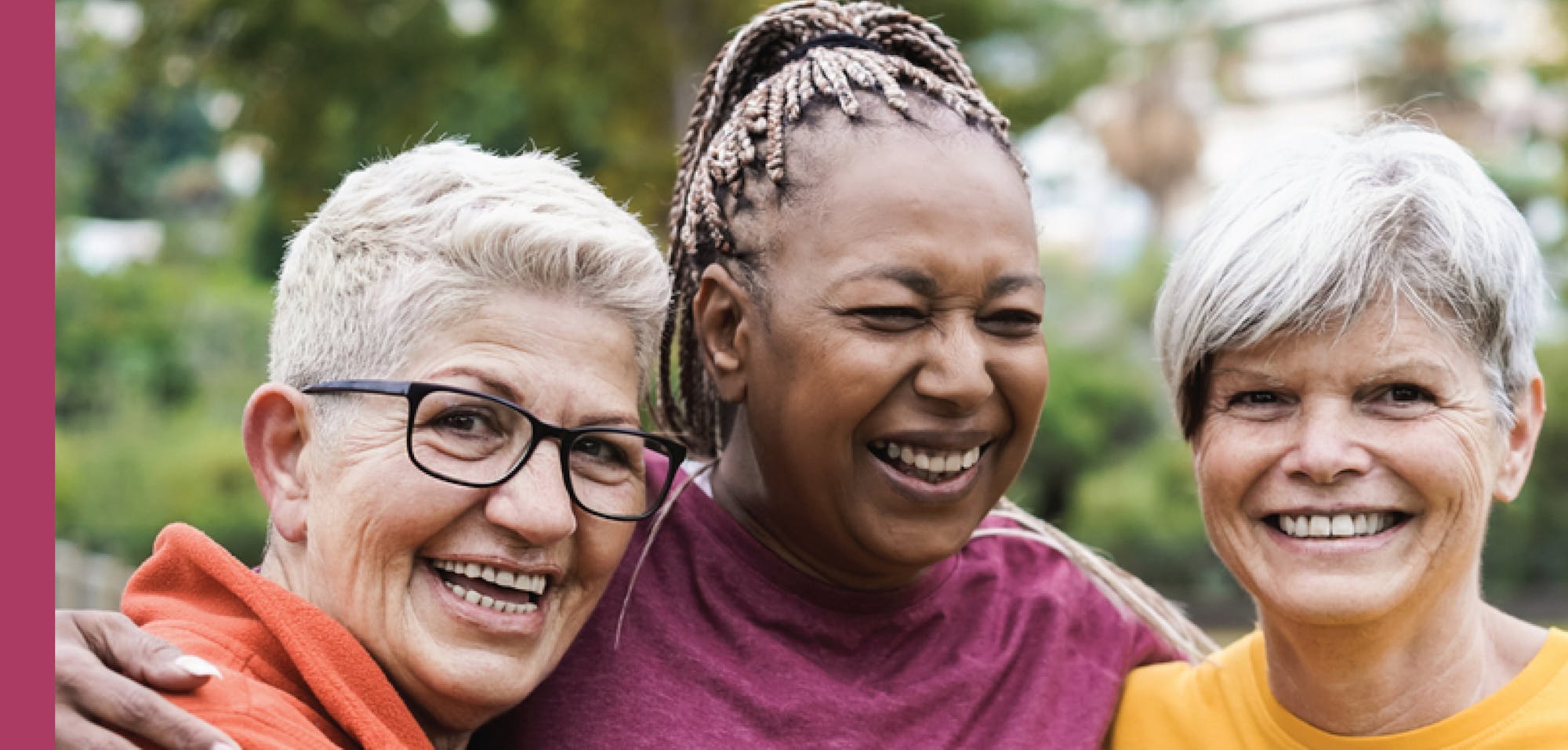 Three happy women embracing and smiling outdoors.