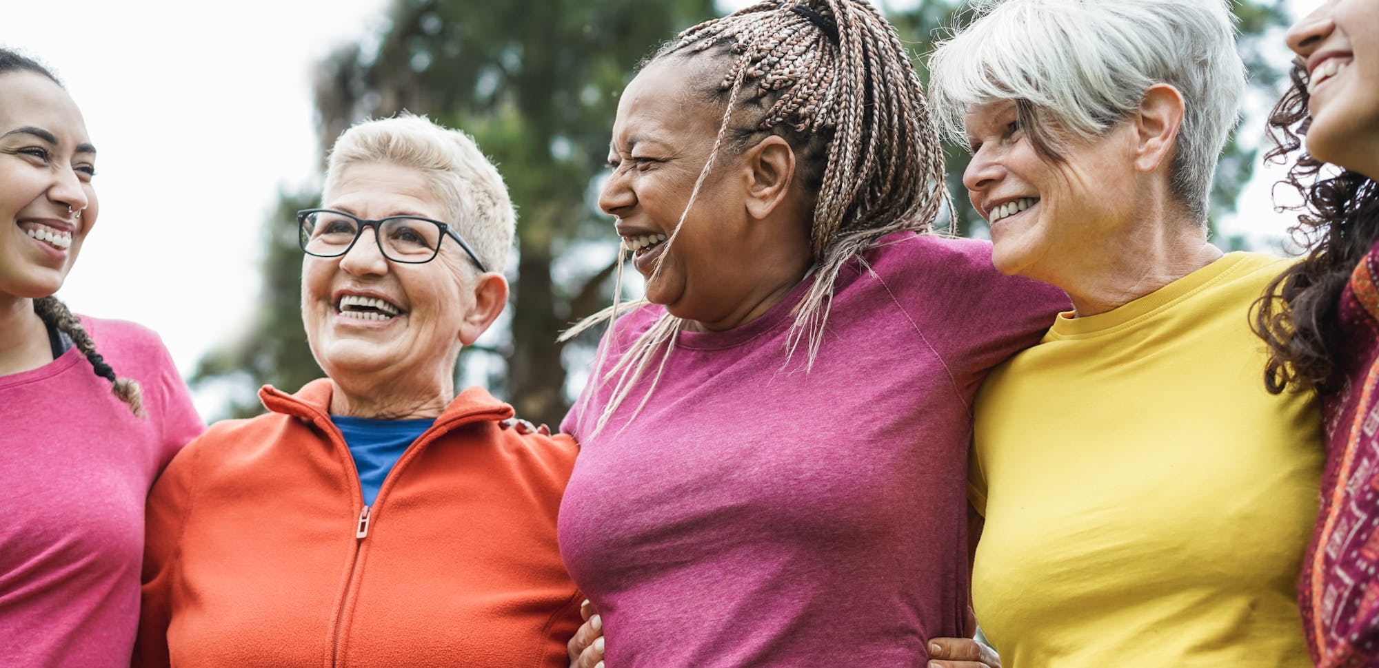 A group of happy, diverse women standing close together smiling, representing friendship or unity.