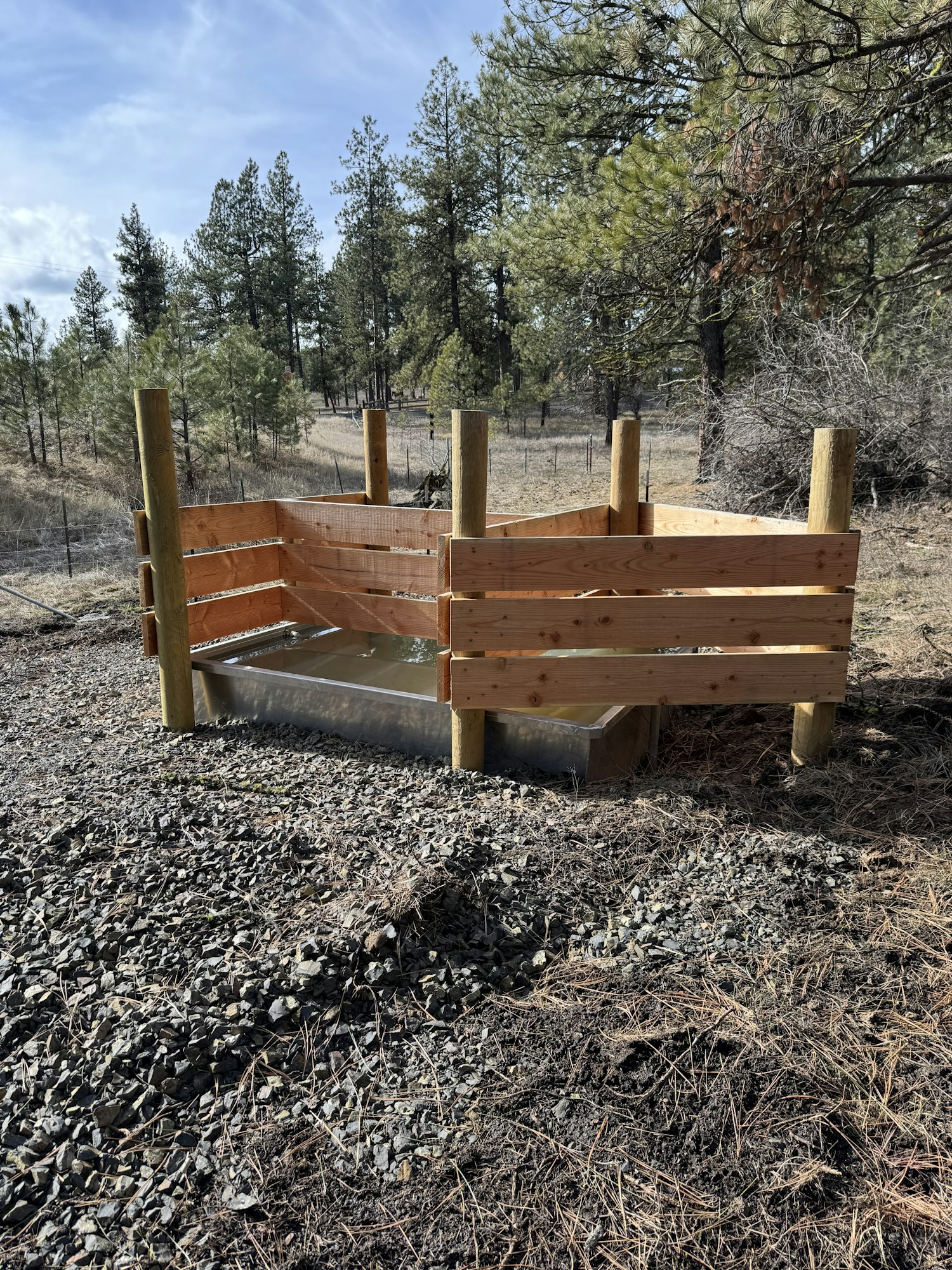 The image shows a wooden spring development structure in a wooded outdoor setting.