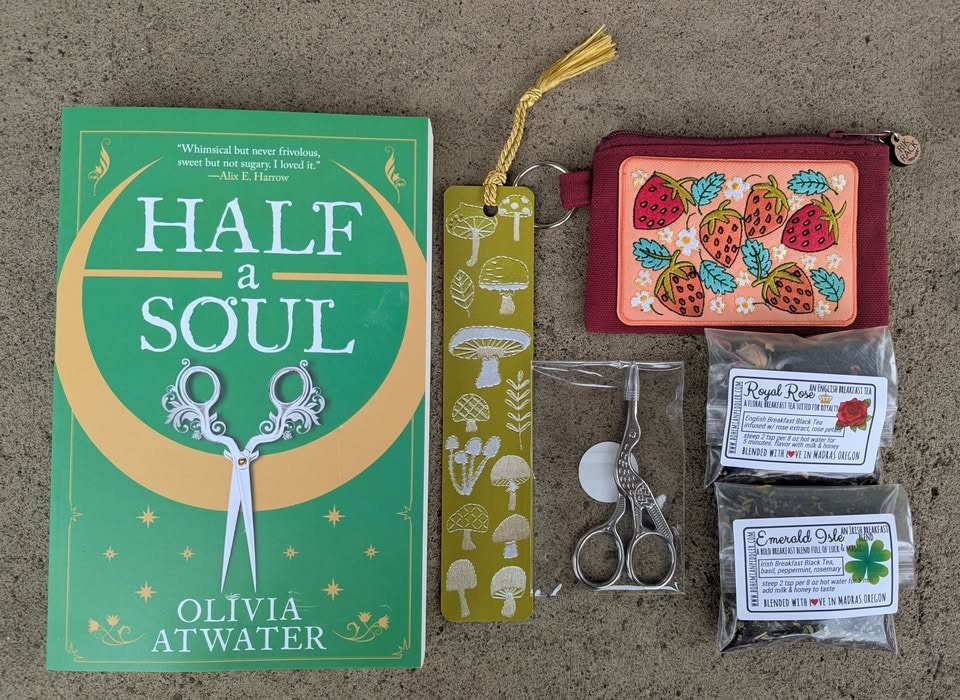 A book "Half a Soul," bookmark, strawberry pouch, scissors, and two tea packets (Royal Rose and Emerald Isle).