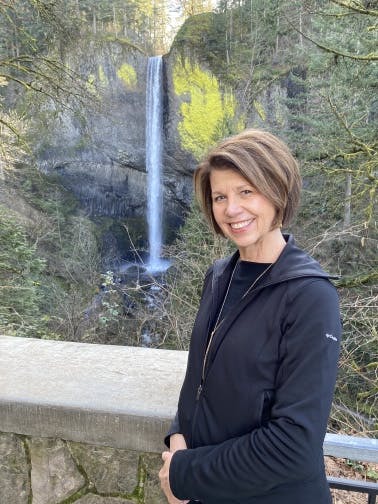 Board member Susan Stovall standing in front of a waterfall.