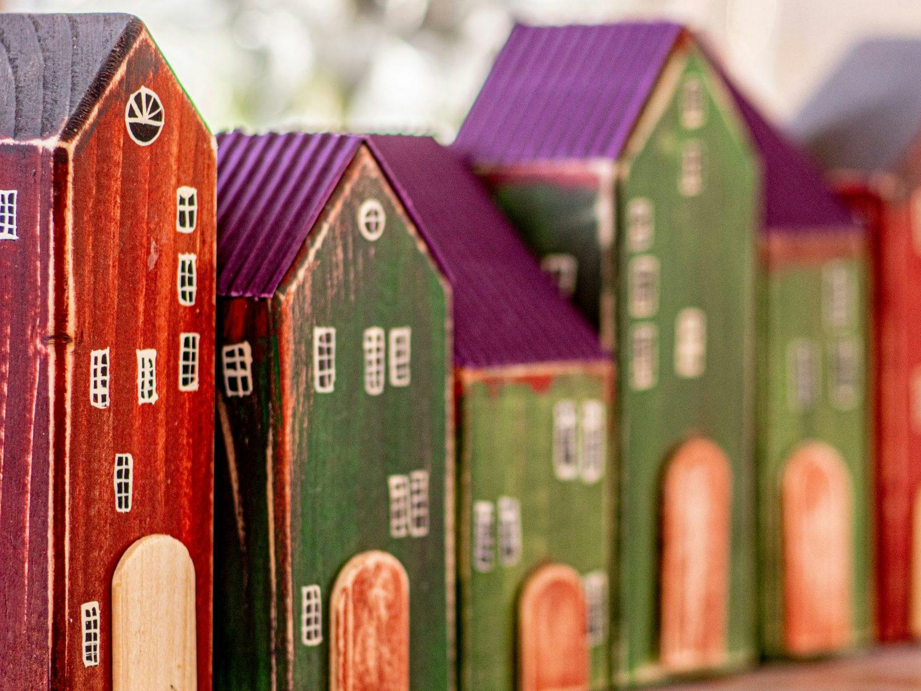 Colorful wooden miniature houses lined up with detailed windows and doors.