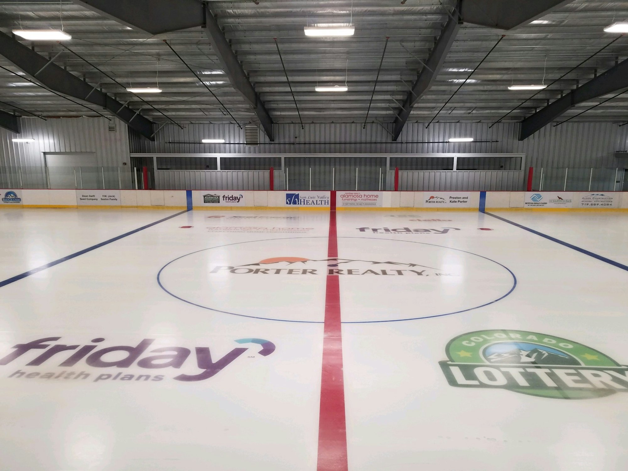 Indoor ice hockey rink with advertising logos on the ice.