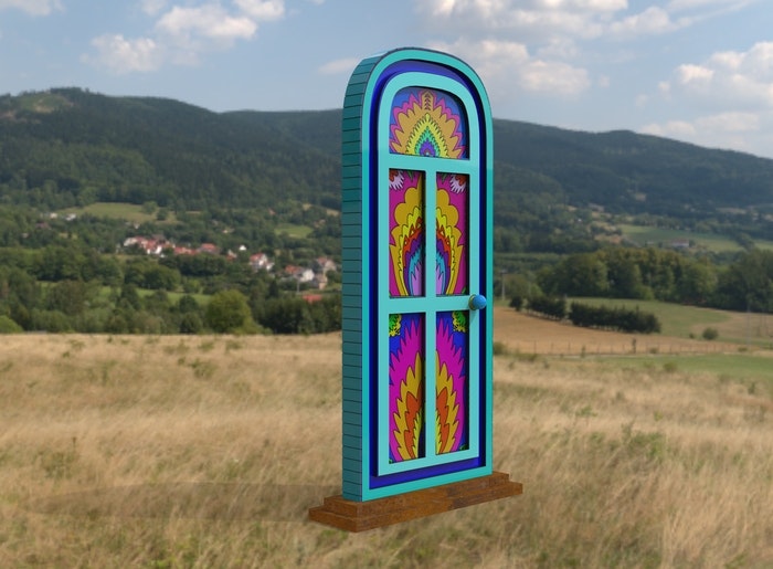 A colorful, psychedelic arched door stands alone in a grassy field with mountains in the background.