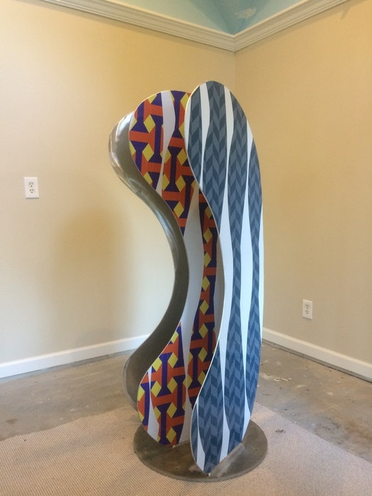 A colorful abstract sculpture with wavy, patterned surfaces in a room.
