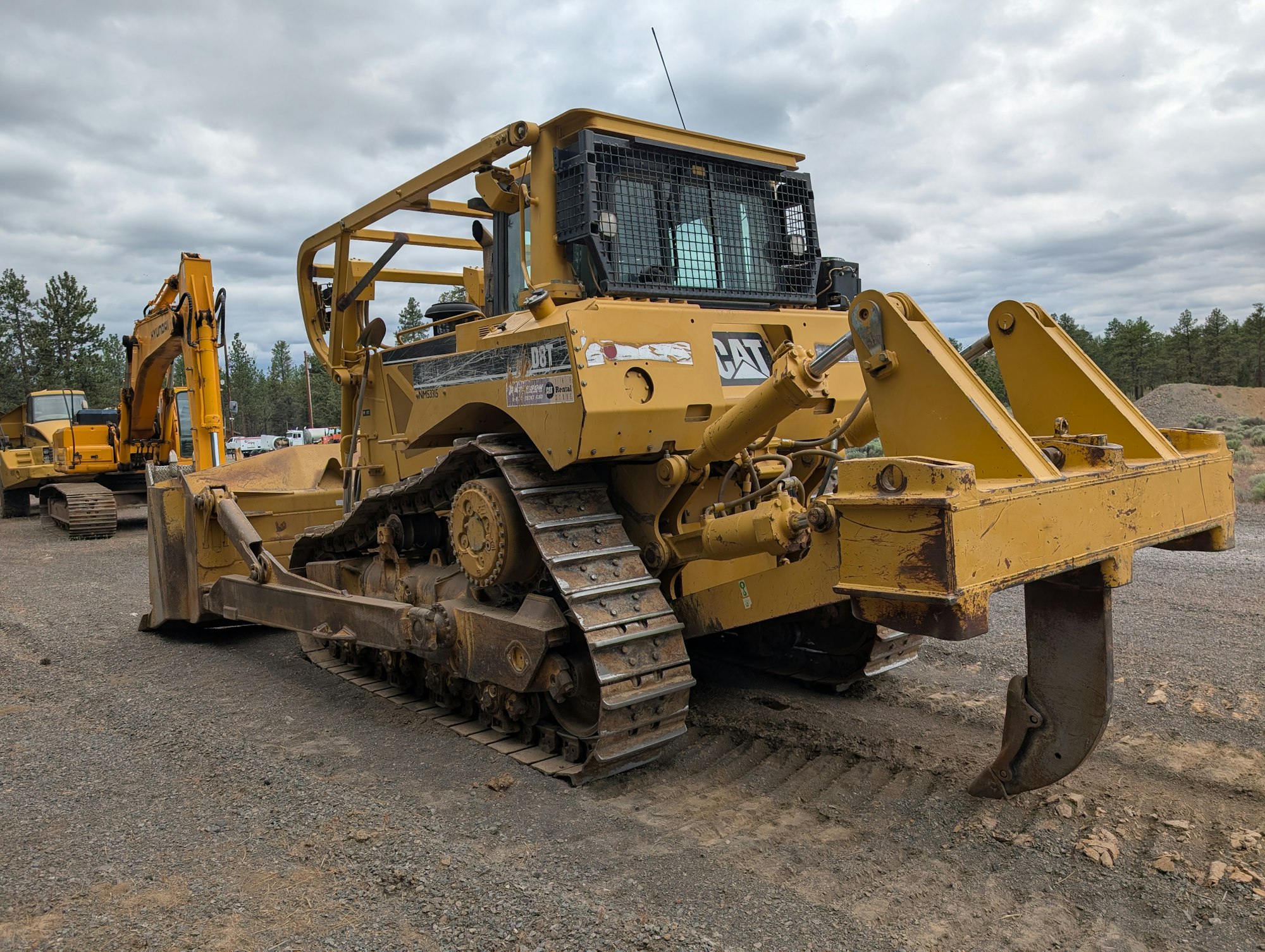 The image shows a yellow Caterpillar bulldozer with tracks, used for construction, parked on a gravel surface.
