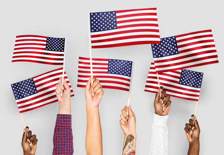 Multiple hands of diverse individuals holding American flags against a neutral background.