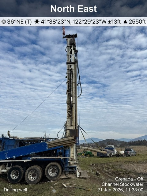 The image shows a drilling rig set up in a landscape, with equipment and machinery for well drilling.