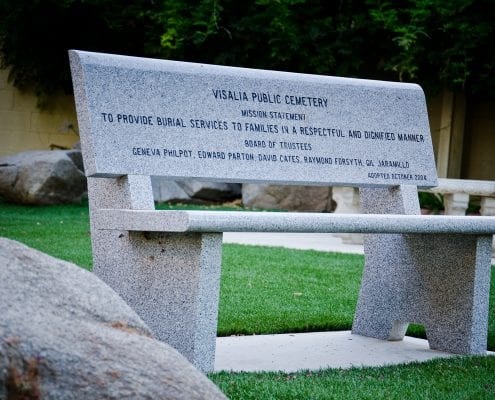 Granite bench with an inscription from "Visalia Public Cemetery" including a mission statement and names of trustees.