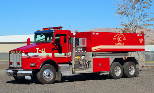 A red fire tanker truck with emergency lights and firefighting equipment.