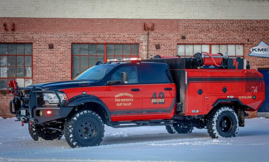 A red firefighting brush truck parked on snow.