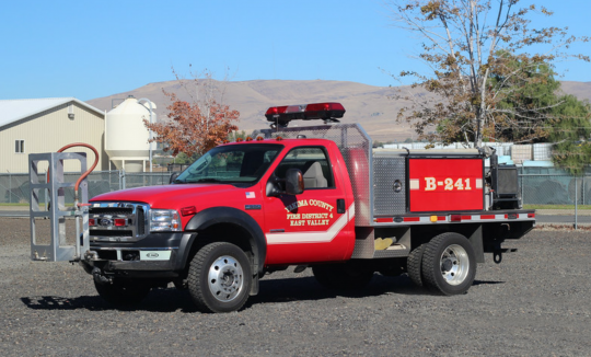 A red fire department brush truck with equipment.