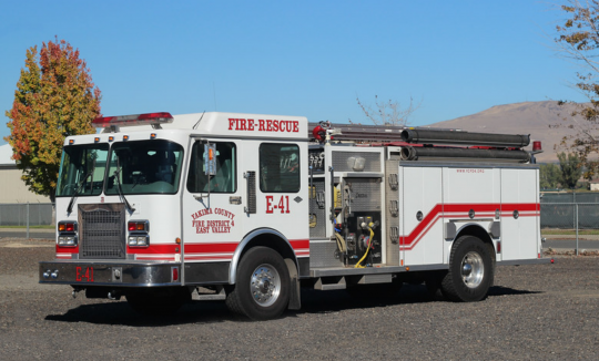 A parked fire-rescue truck with open compartments, displaying firefighting equipment inside.