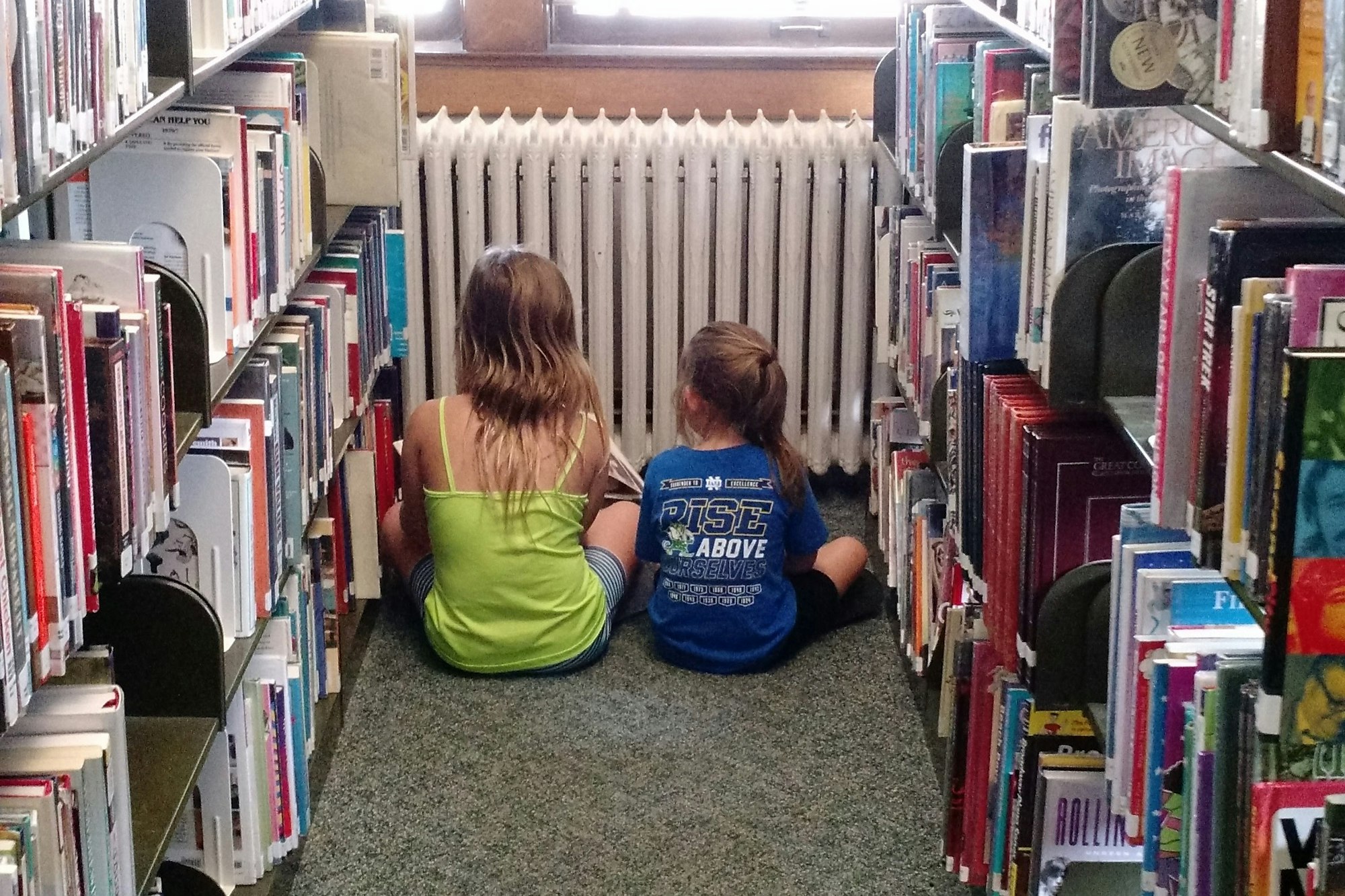 May contain: library, book, publication, indoors, person, shelf, child, girl, and female