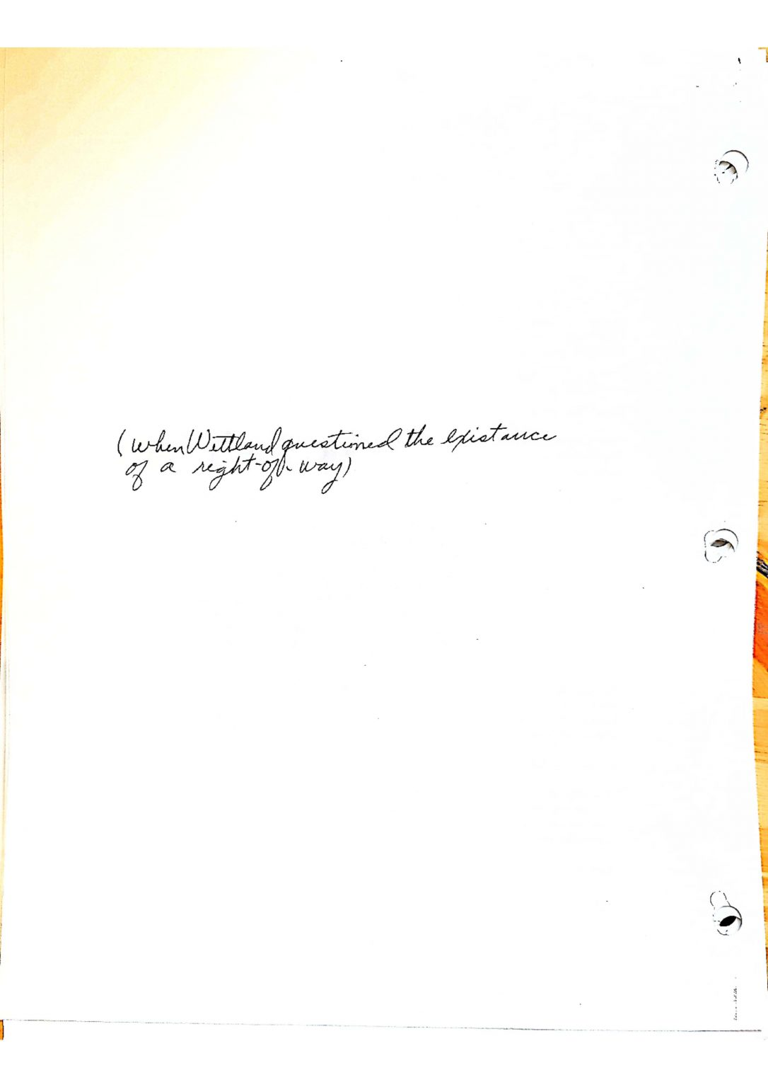 A page with handwritten text and three punched holes on the side.
