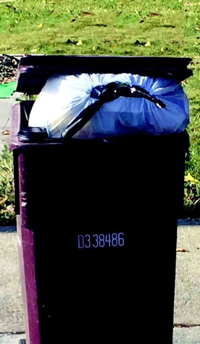 An overflowing trash bin with a white garbage bag on top, lid partly open.