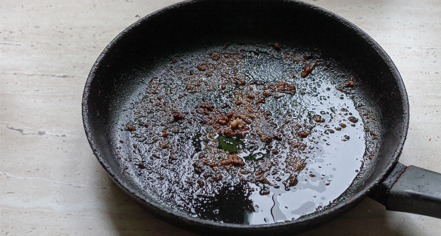 A dirty frying pan with oil and food residue.