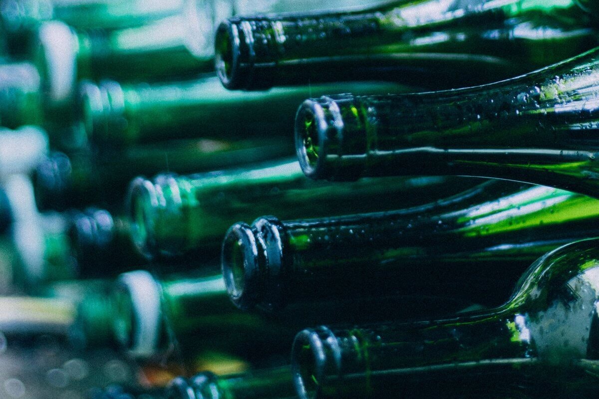 Stacked green glass bottles lying horizontally.