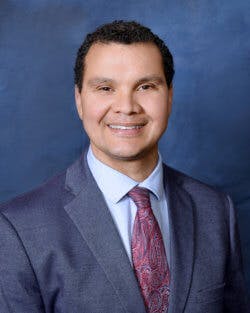 A person in a suit and tie with a blue background.