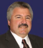 A person in a suit and tie against a blue background.
