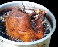 A turkey being deep-fried in a pot of hot oil.