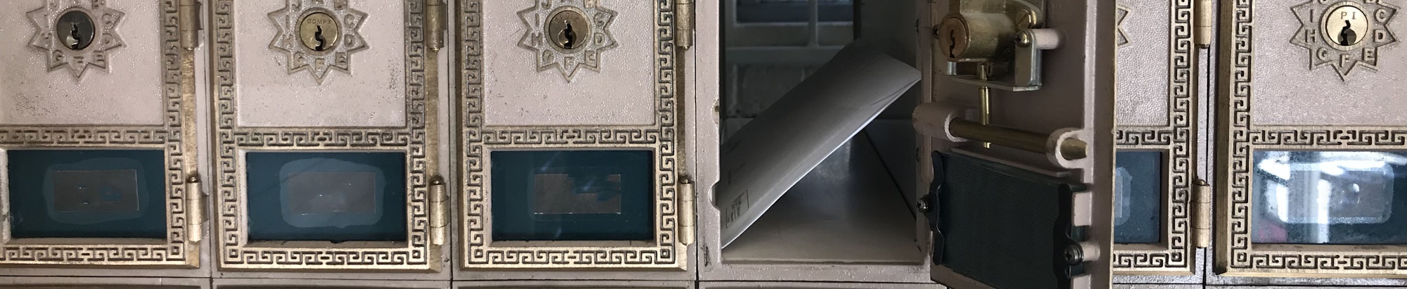 Row of mailboxes with intricate designs, one open with mail visible.
