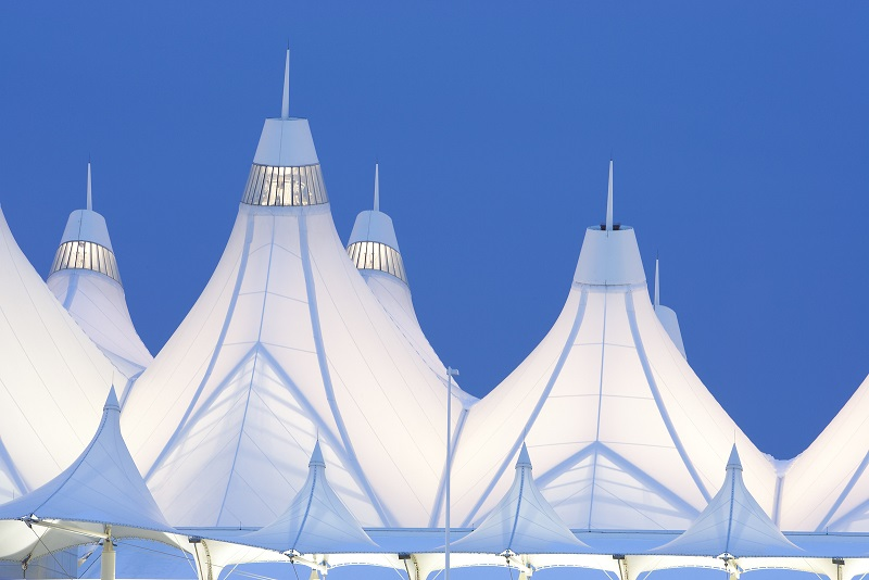 The image features a series of white, tent-like structures against a blue sky, suggesting modern architectural design.