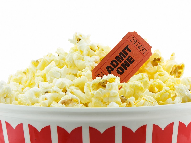 A bowl of popcorn with a red movie admission ticket partially sticking out. Perfect for a movie night!