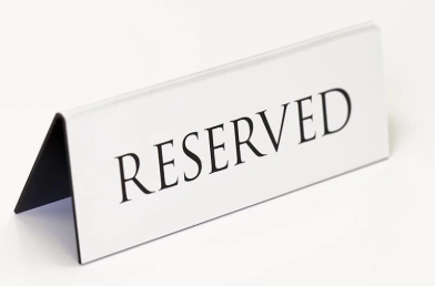 A table tent sign displaying the word "RESERVED" in bold, indicating that the space is kept for a specific use or individual.