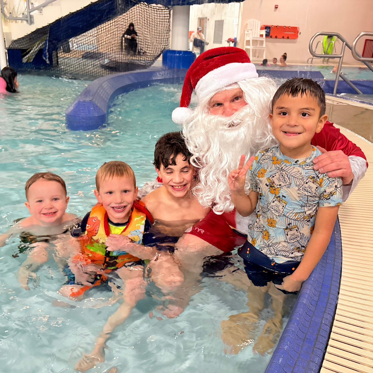 A group of children in a pool with Santa Claus, enjoying a fun and festive moment together.