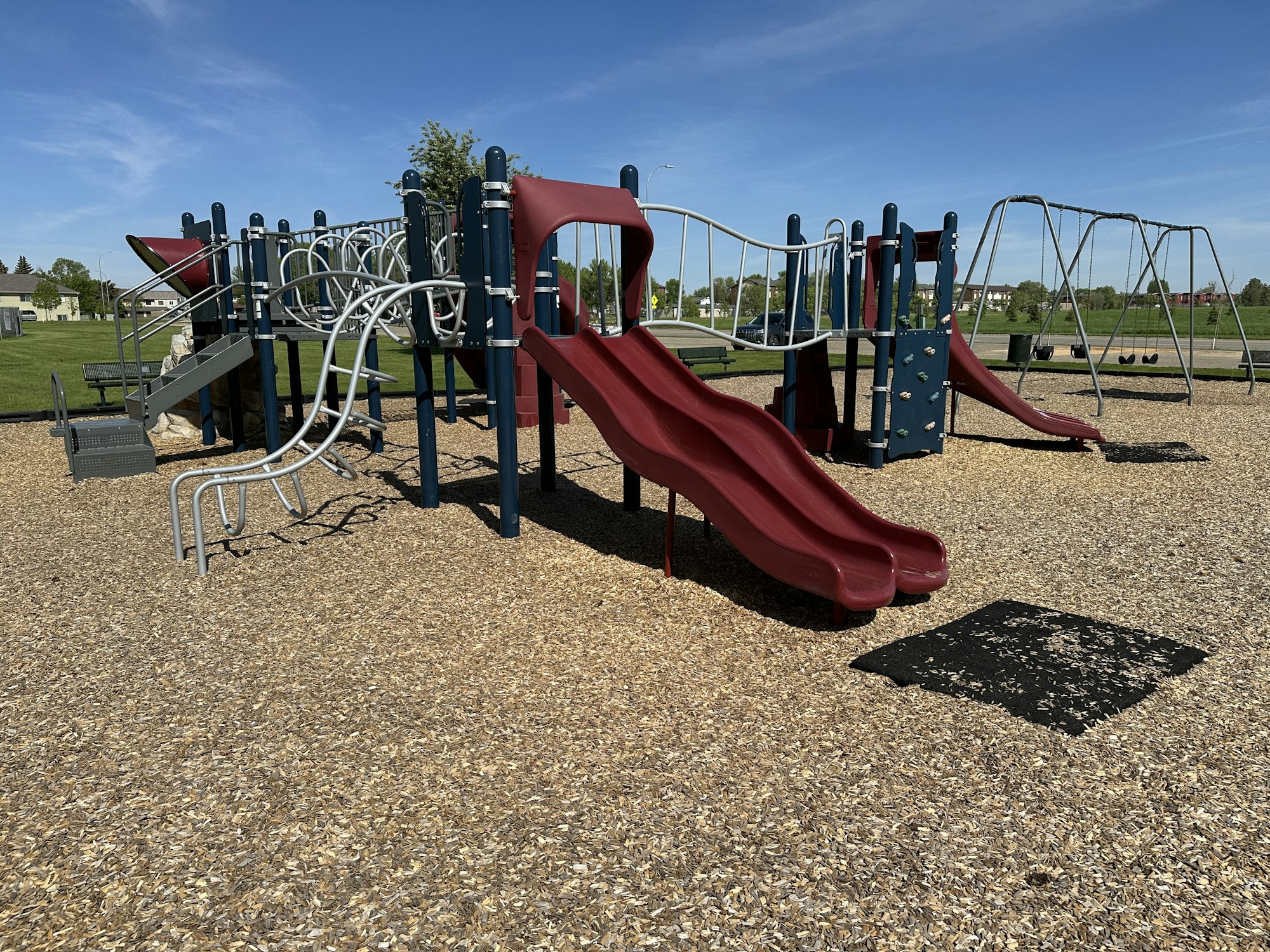 A playground with slides, swings, and climbing structures on a sunny day.