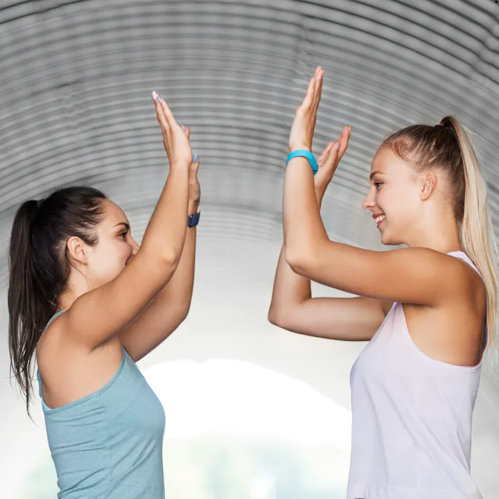 Two women high-fiving in a tunnel-like structure.