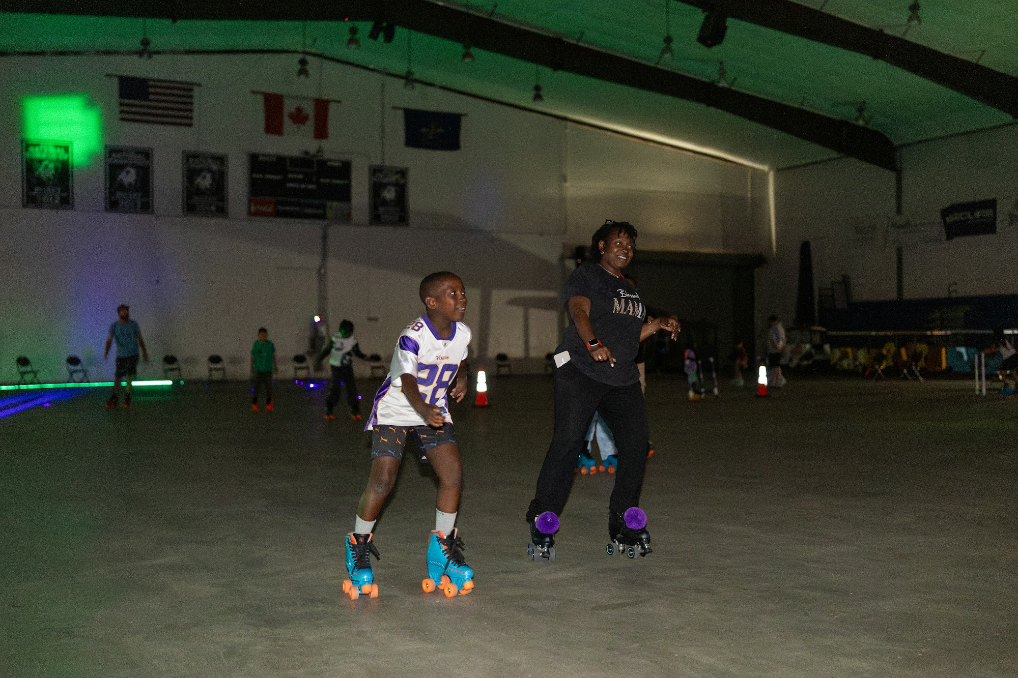 People roller skating indoors, with lights and flags in the background.