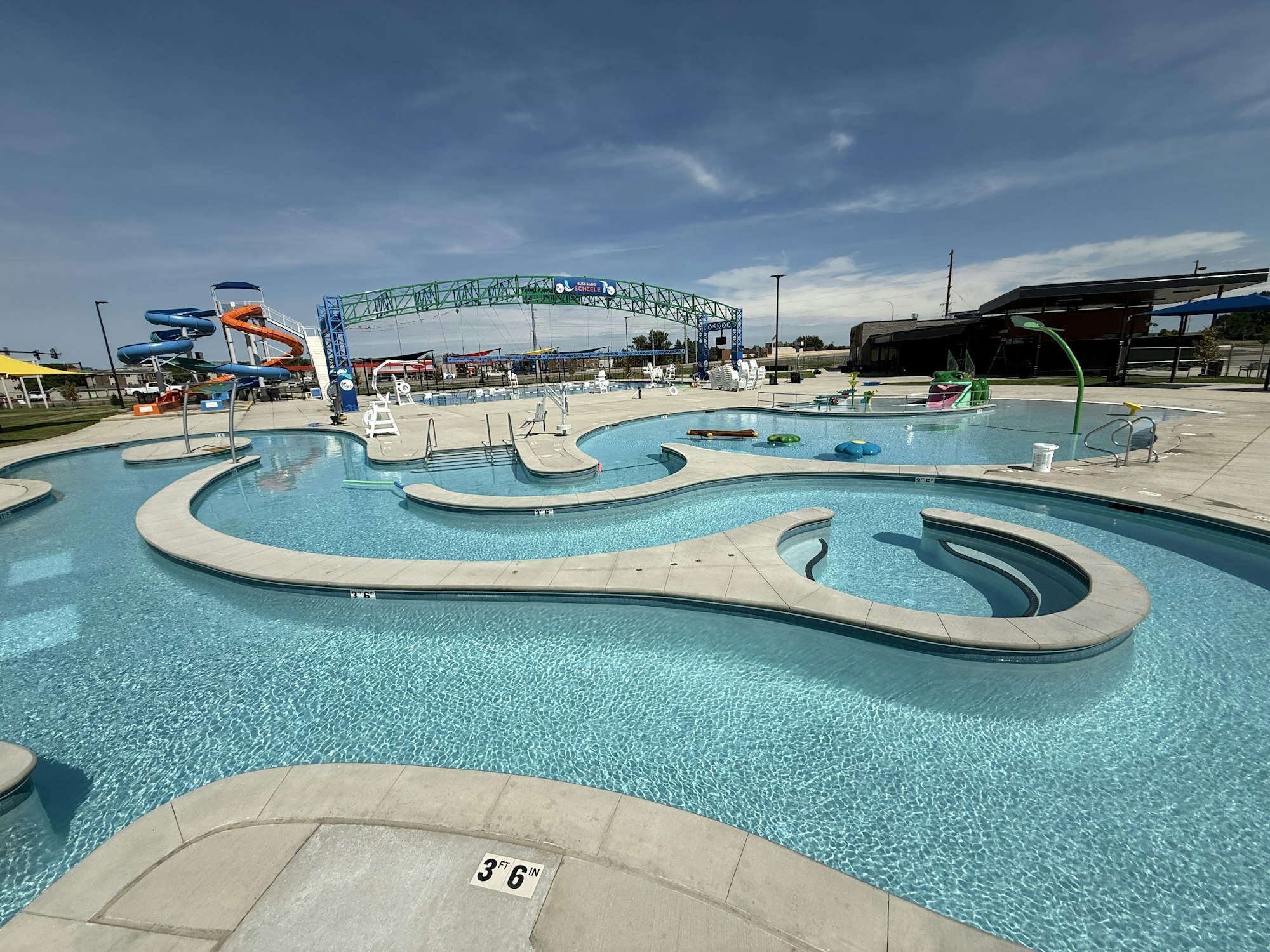 Outdoor water park with winding lazy river, water slides, lounge areas, and overhead structures.