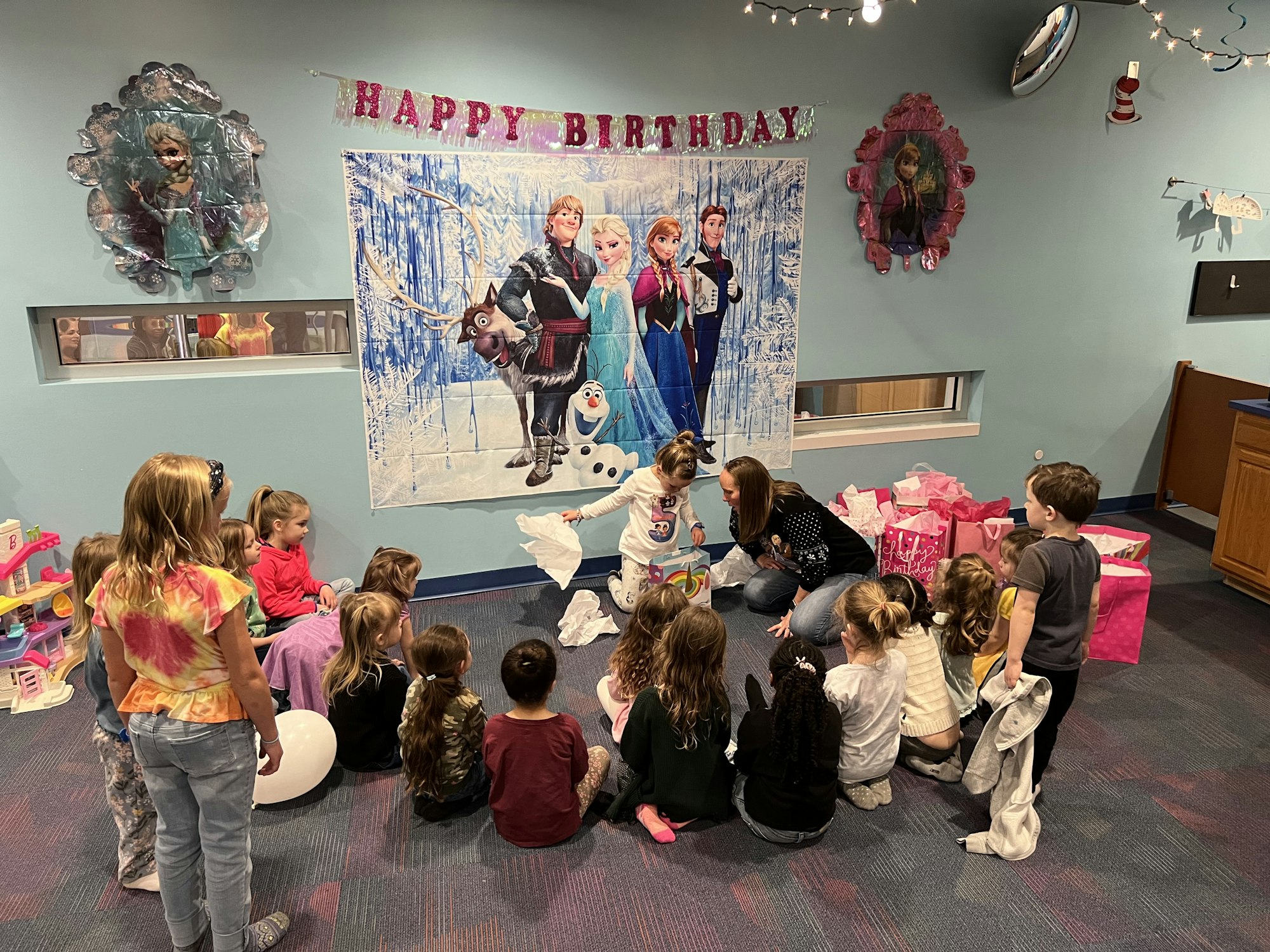 Children's birthday party with decorations and gifts, featuring a backdrop from an animated film.