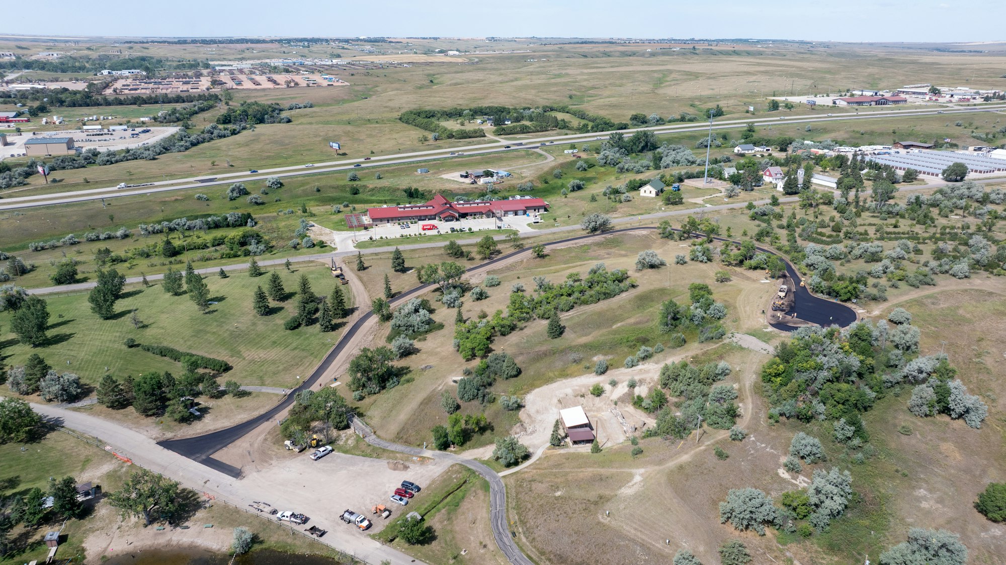 An aerial view of a landscape with buildings, roads, and greenery, featuring a mix of developed and open land.