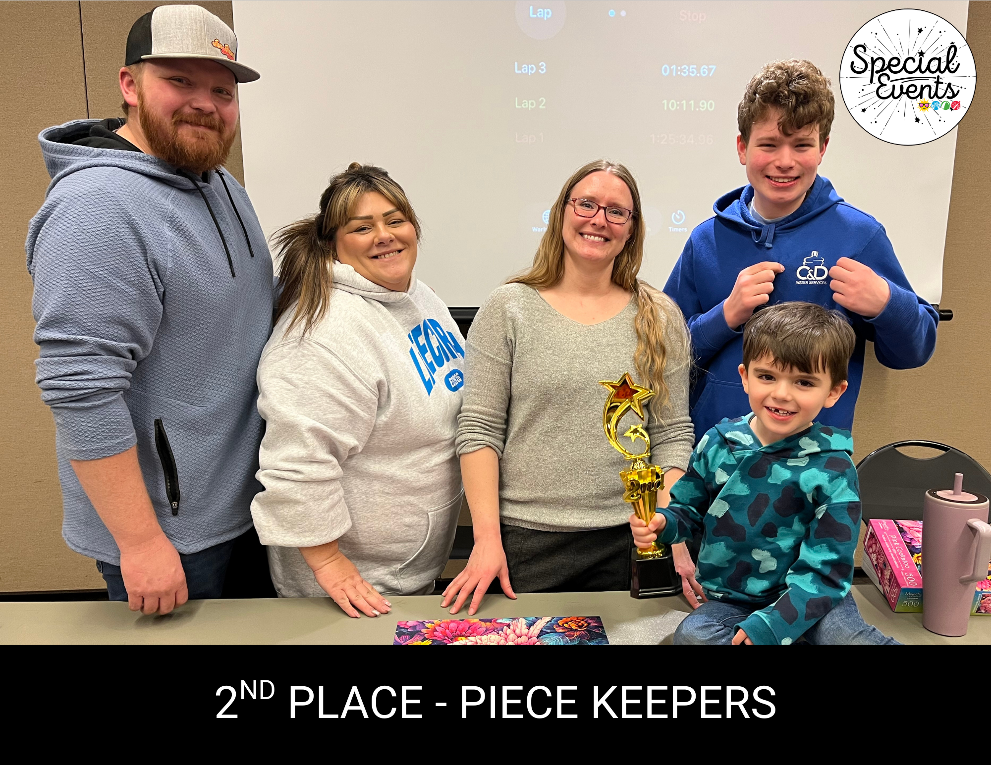 A group of five people celebrates a second-place win, holding a trophy labeled "Piece Keepers."