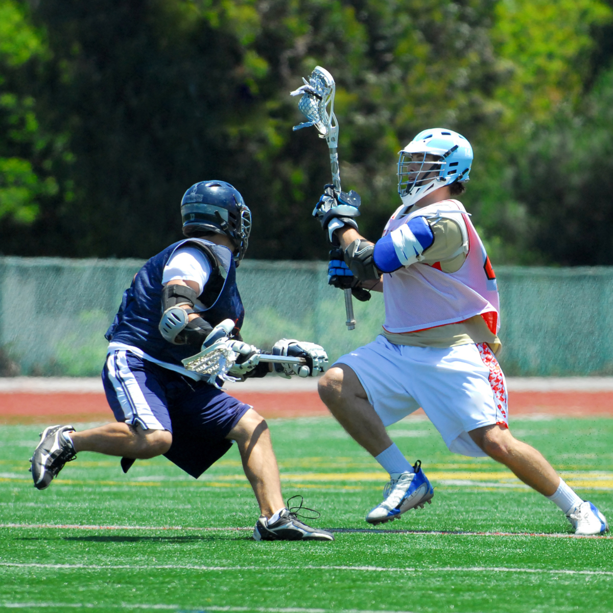Two lacrosse players in action on a field.