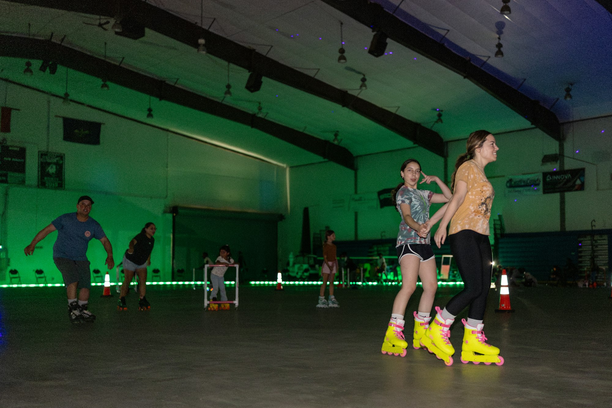 People roller skating indoors with colorful lights and cones.
