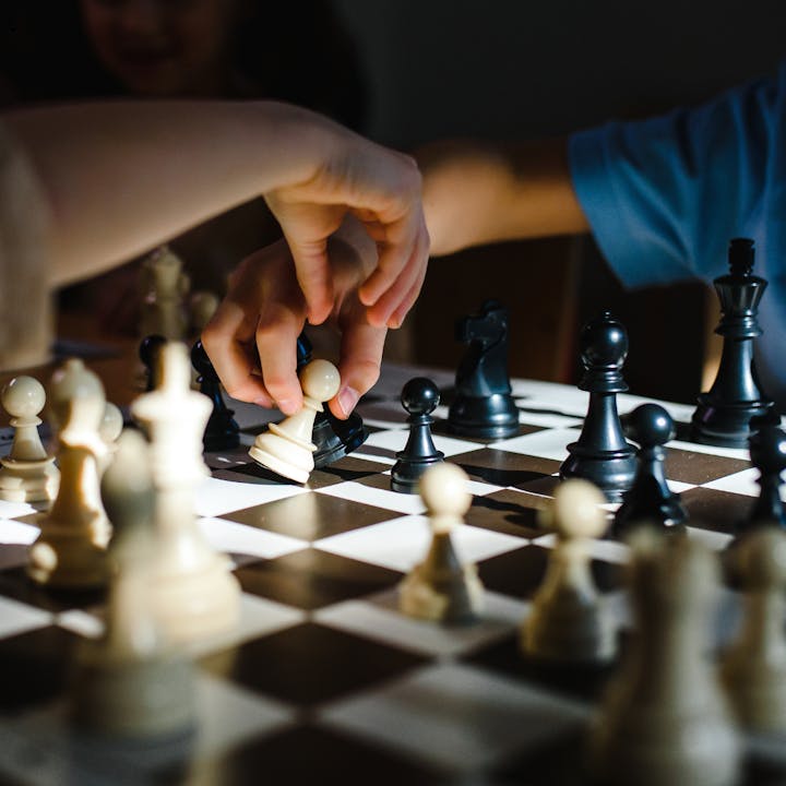 Hands moving chess pieces on a chessboard.