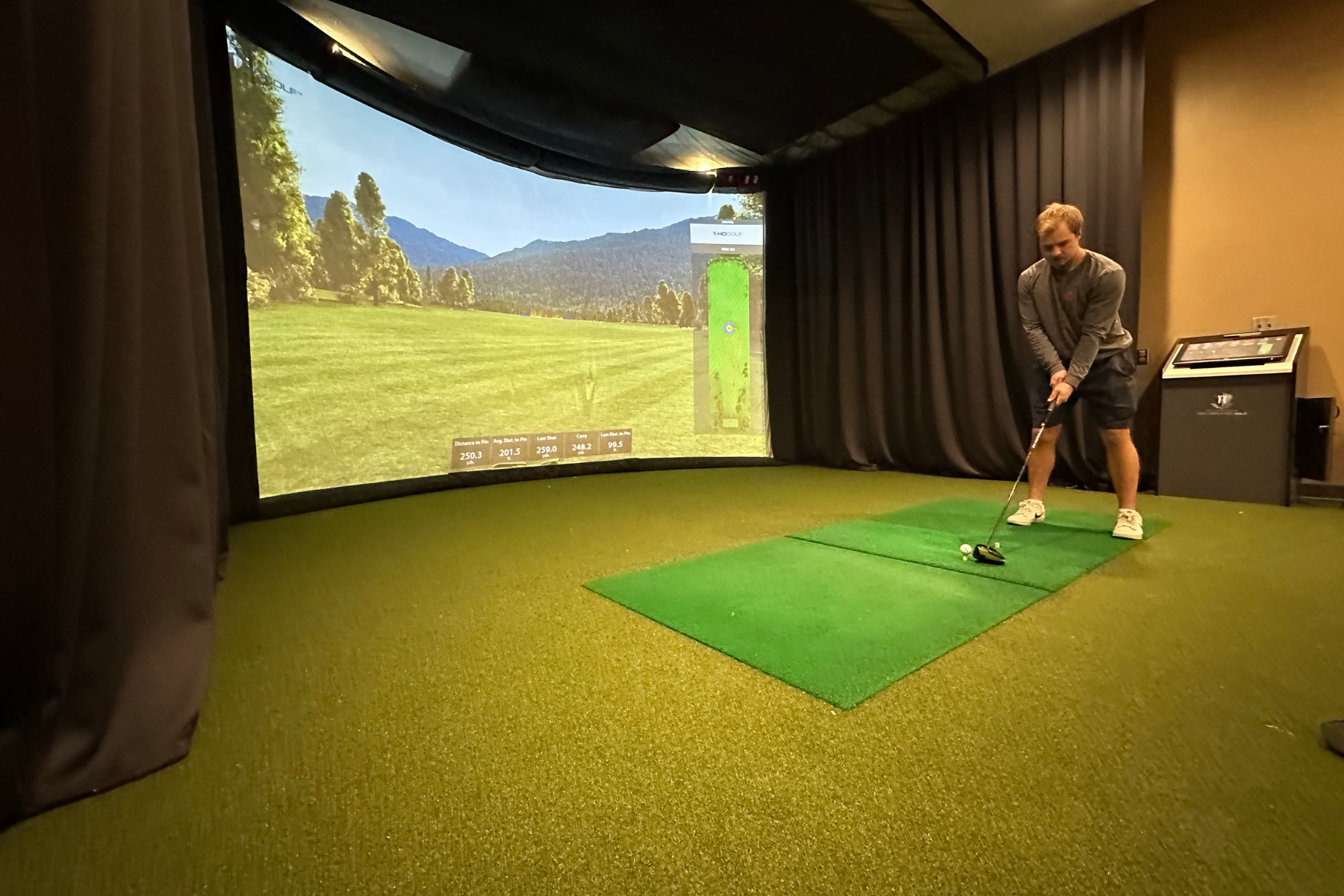 A person playing on a golf simulator indoors.