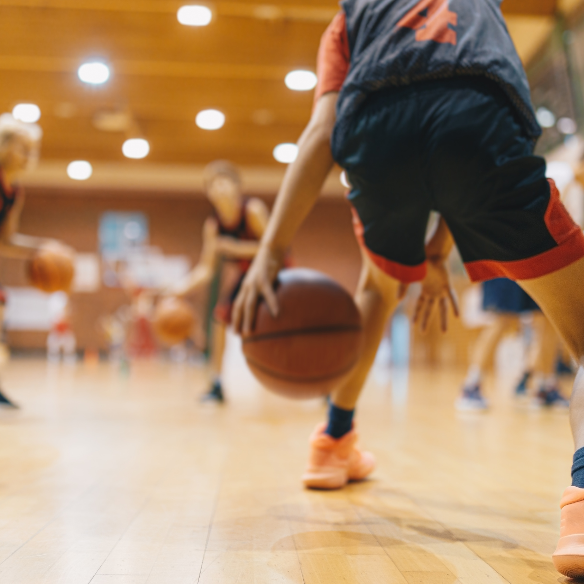 A blurry indoor basketball game in progress with a focus on a player dribbling the ball.