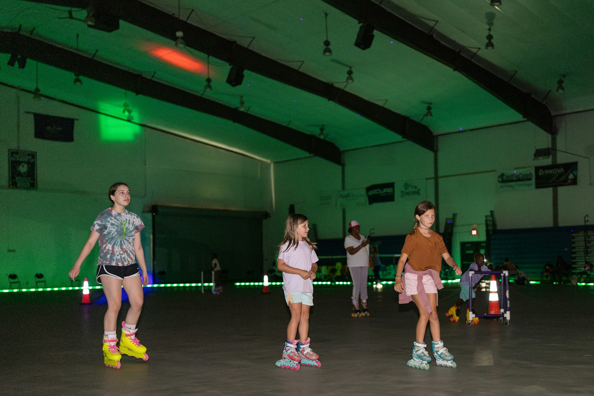 People roller skating indoors under colorful lights.